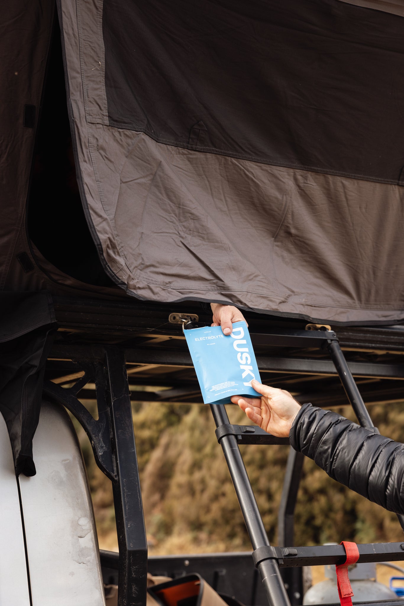 Person reaching for Dusky Electrolyte Capsules at a campsite before an outdoor adventure in New Zealand. 