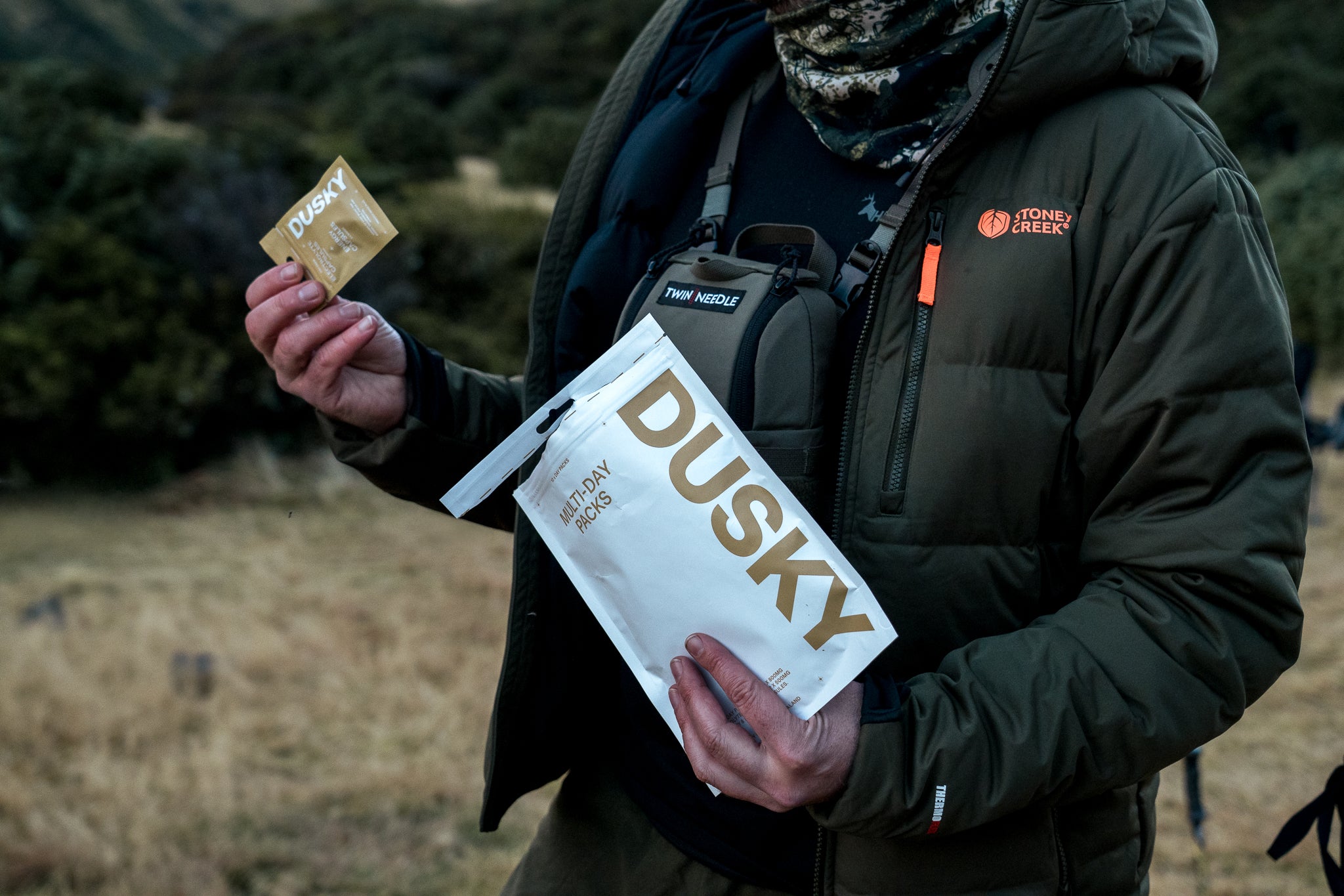 Hunter holding a Dusky Day Pack containing electrolyte and energy capsules during an outdoor adventure in New Zealand. 